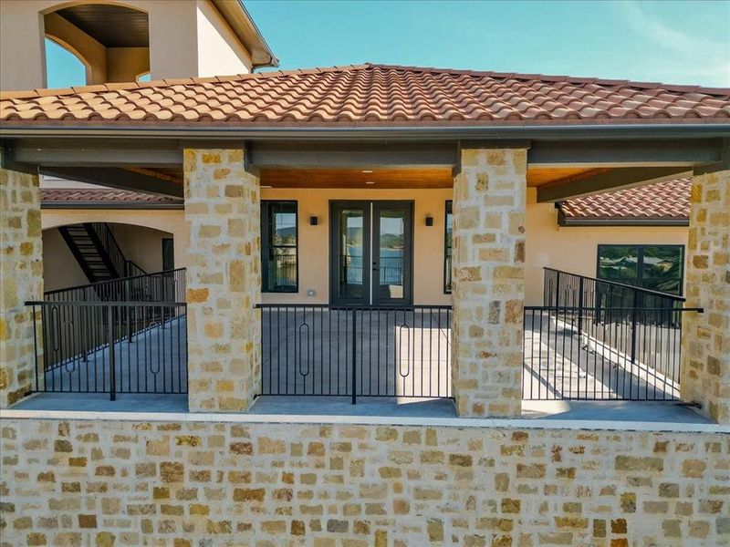Doorway to property featuring stucco siding, a tile roof, and stone siding Doorway to property featuring stucco siding, a tile roof, and stone siding