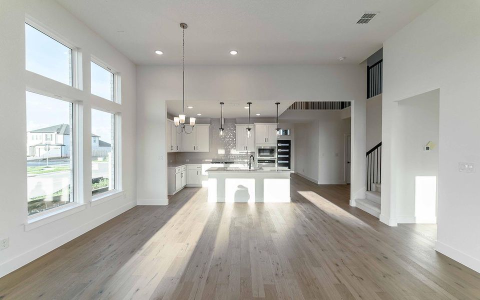 Unfurnished living room with plenty of natural light, a chandelier, wood finished floors, stairway, and recessed lighting