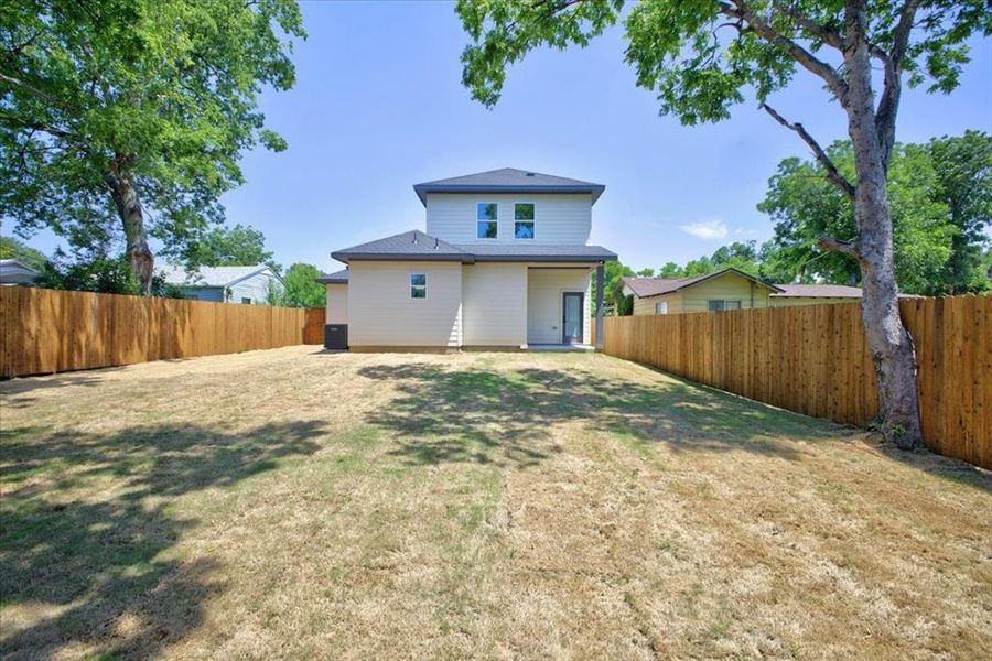 Expansive backyard featuring a new privacy fence, mature trees, and a two-story home with a contemporary exterior Expansive backyard featuring a new privacy fence, mature trees, and a two-story home with a contemporary exterior