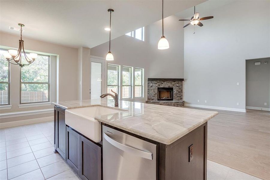 Kitchen featuring stainless steel dishwasher, a center island with sink, and a high ceiling