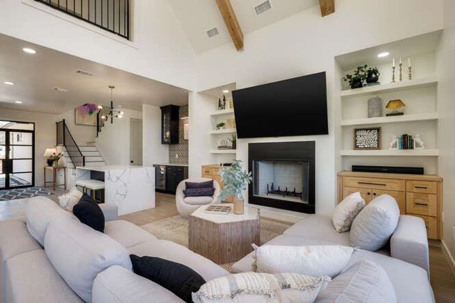 Living area featuring recessed lighting, beamed ceiling, stairway, high vaulted ceiling, and a fireplace