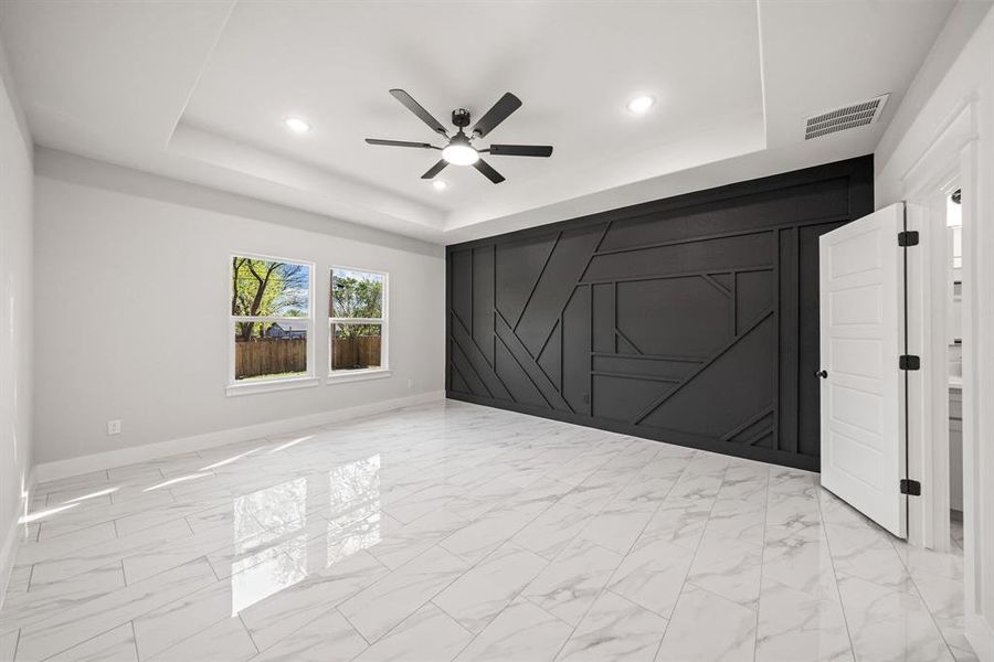 Unfurnished bedroom with light marble finish floors, a decorative wall, a ceiling fan, recessed lighting, and an accent wall