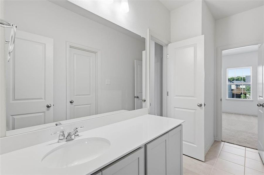 Bathroom with vanity, light tile patterned floors, and light colored carpet Bathroom with vanity, light tile patterned floors, and light colored carpet