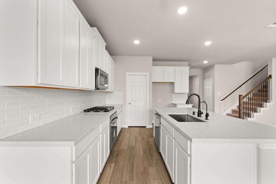 Kitchen with plenty of counterspace features white cabinetry, quartz countertops and a modern tile backsplash