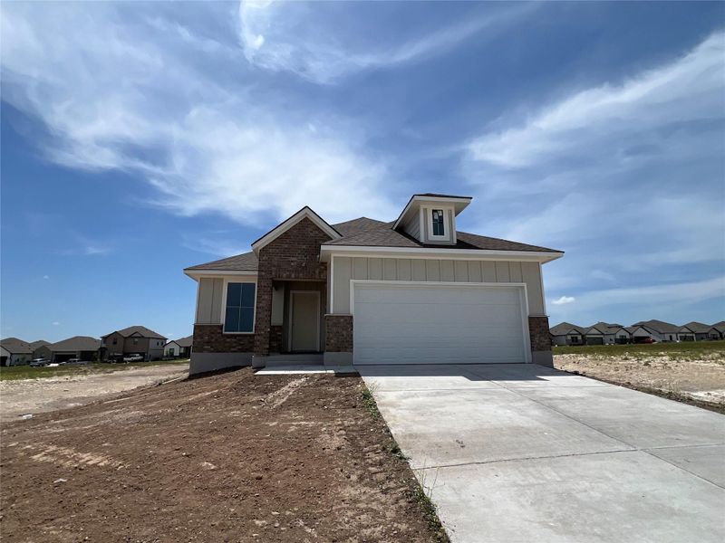 View of front facade with a residential view, a shingled roof, board and batten siding, driveway, and brick siding