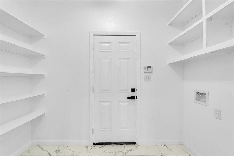 Laundry area featuring washer hookup and light tile patterned flooring