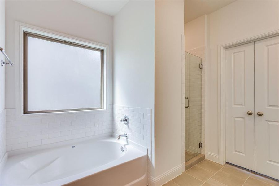 Bathroom featuring plus walk in shower, a wealth of natural light, and tile patterned flooring