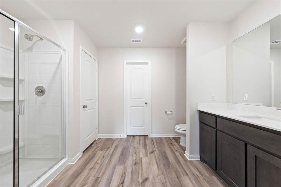 Full bathroom with wood finished floors, vanity, a shower stall, toilet, and baseboards