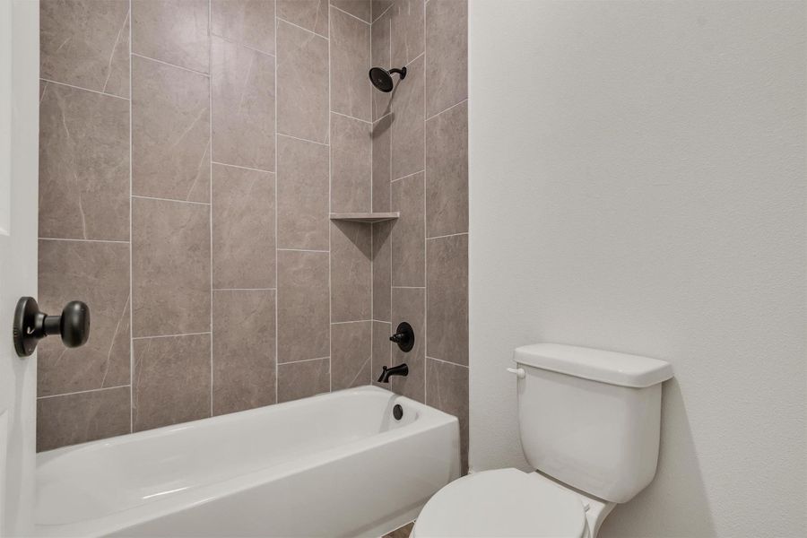 Modern full bathroom with sleek tile tub surround and dark bronze fixtures.