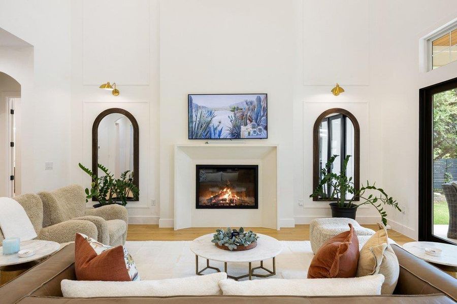 A refined living area boasts a sleek fireplace, flanked by tall arched mirrors, setting a sophisticated tone. A refined living area boasts a sleek fireplace, flanked by tall arched mirrors, setting a sophisticated tone.
