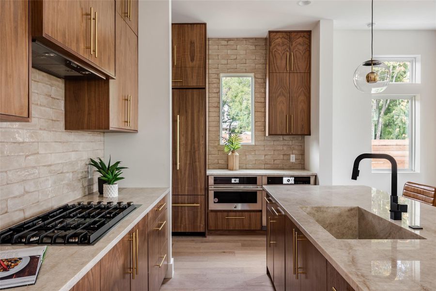 A luxurious quartz sink area complements the high-end gas cooktop, while a sleek vent ensures a polished, functional cooking space, blending style with practicality.