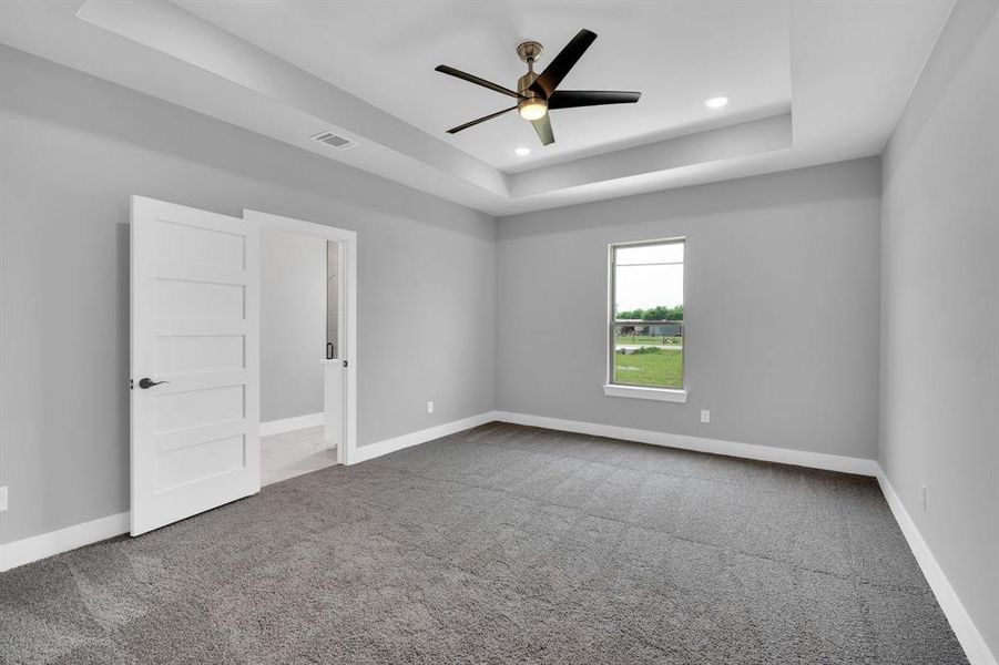 Spare room featuring ceiling fan, a raised ceiling, and carpet