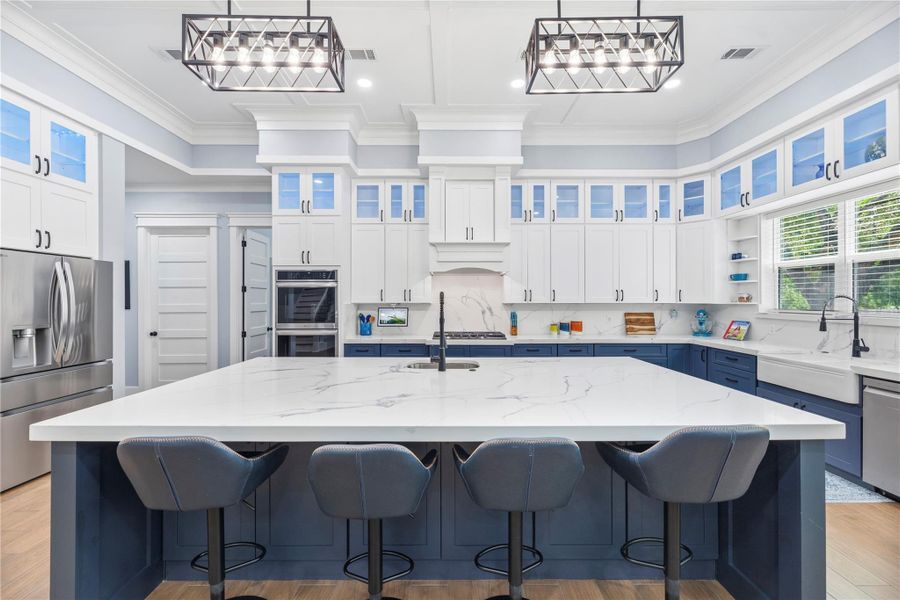 A designer chef’s kitchen takes center stage with an oversized island, custom cabinetry, statement lighting, and an open-concept layout tailored for elevated entertaining.