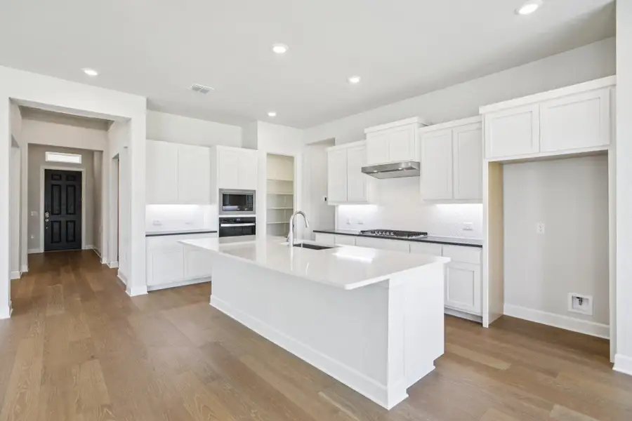 Kitchen with backsplash, white cabinetry, recessed lighting, a kitchen island with sink, and light wood-type flooring