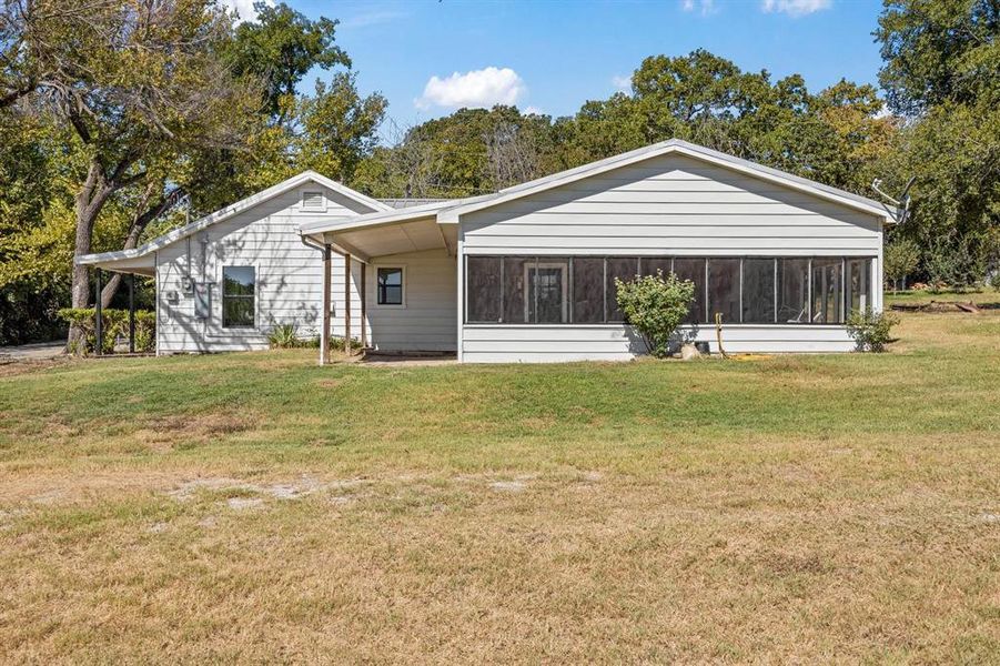 Back of property featuring a sunroom and a yard