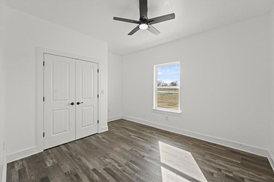 Unfurnished bedroom featuring dark wood-type flooring, a closet, and ceiling fan