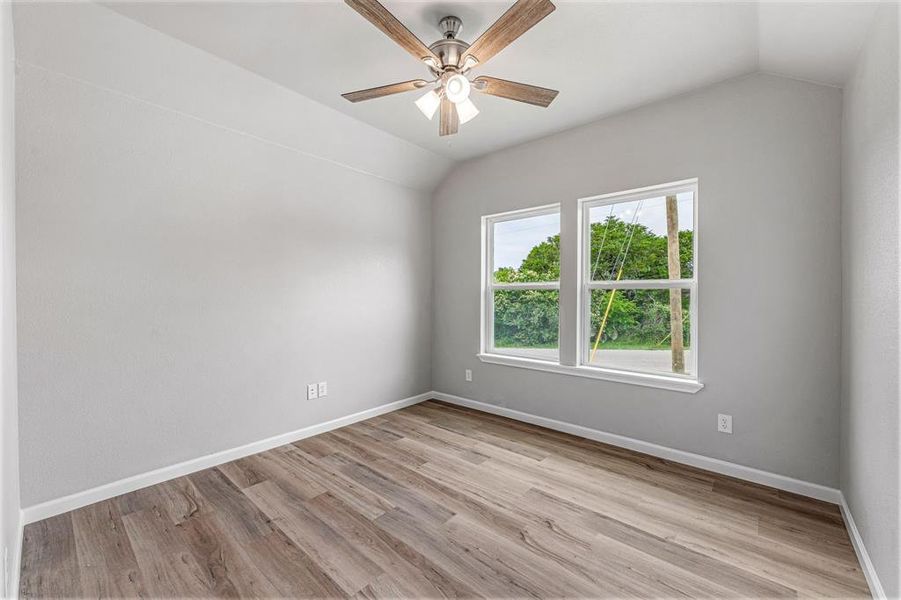Unfurnished room with lofted ceiling, light wood-style floors, a ceiling fan, and baseboards Unfurnished room with lofted ceiling, light wood-style floors, a ceiling fan, and baseboards