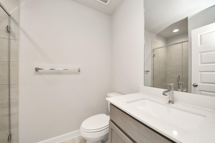 Secondary bath features tile flooring, walk-in shower with tile surround, light stained wood cabinets, beautiful light countertop. Sample photo of completed home with similar floor plan. Actual colors and selections may vary. Secondary bath features tile flooring, walk-in shower with tile surround, light stained wood cabinets, beautiful light countertop. Sample photo of completed home with similar floor plan. Actual colors and selections may vary.