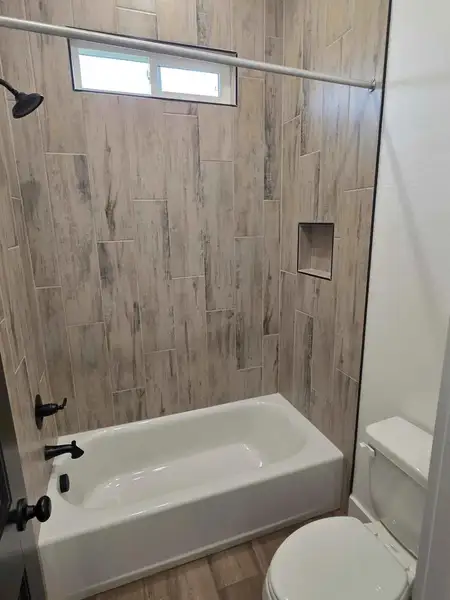 Bathroom with bathing tub / shower combination and wood finished floors Bathroom with bathing tub / shower combination and wood finished floors