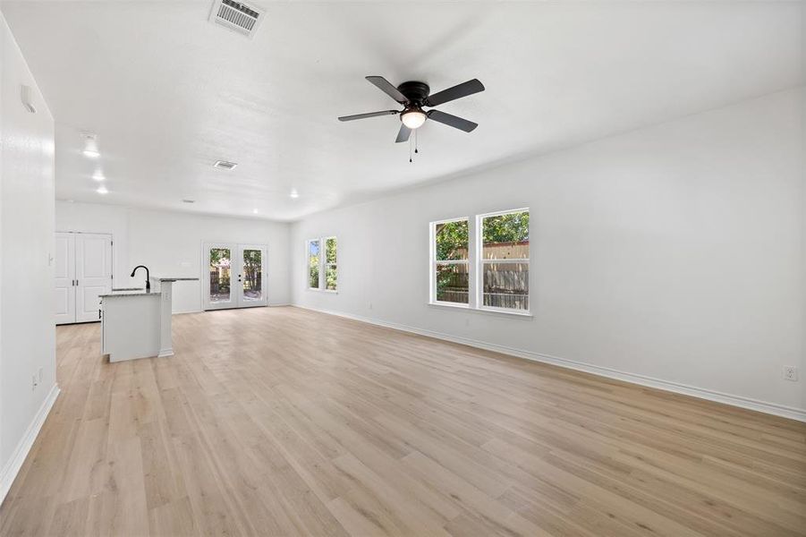 Unfurnished living room featuring light wood-type flooring, french doors, and a ceiling fan