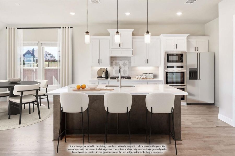 Open kitchen with white cabinets, large island with seating, stainless appliances, and adjacent dining area with hardwood floors