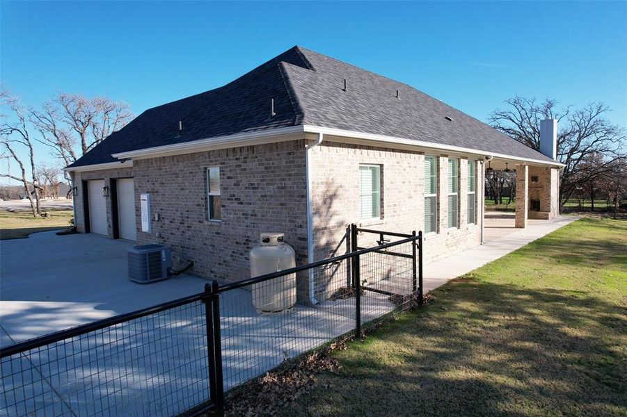 View of home's exterior with central air condition unit, a lawn, a patio, and a garage