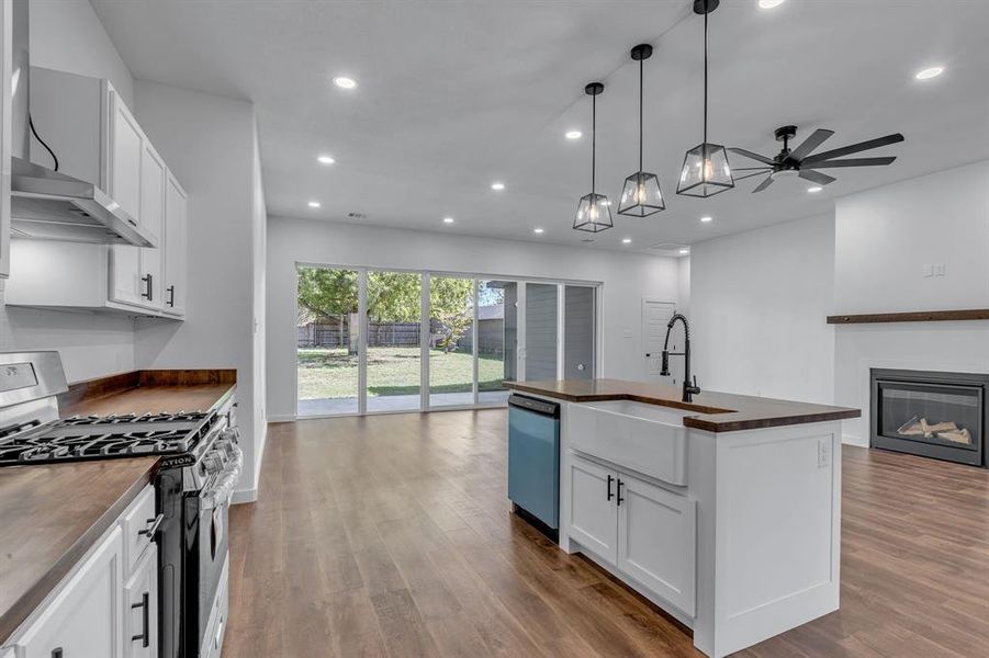 Kitchen with a center island with sink, wooden counters, appliances with stainless steel finishes, sink, and white cabinets