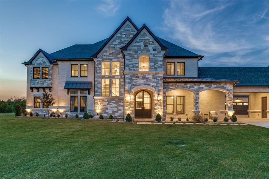 French country home with a standing seam roof, a lawn, and stone siding French country home with a standing seam roof, a lawn, and stone siding