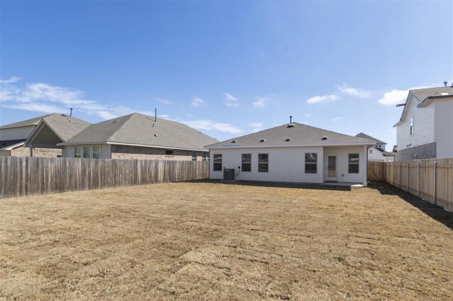 Back of property with a yard, central AC, and a fenced backyard