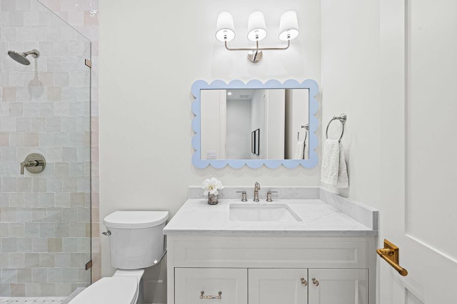 Serving secondary bedroom #2, this en suite bath features a quartz countertop vanity w/ storage below & a Visual Comfort sconce. The shower includes a frameless glass enclosure, Zellige tile surround & a basketweave-patterned tile floor, complemented by a quartz threshold & built-in niche. Thoughtful details throughout create a clean, elevated finish. Serving secondary bedroom #2, this en suite bath features a quartz countertop vanity w/ storage below & a Visual Comfort sconce. The shower includes a frameless glass enclosure, Zellige tile surround & a basketweave-patterned tile floor, complemented by a quartz threshold & built-in niche. Thoughtful details throughout create a clean, elevated finish.