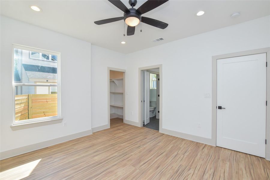 Primary bedroom main level with ensuite bathroom. Walk-in closet. Ceiling fan & recessed can lighting.