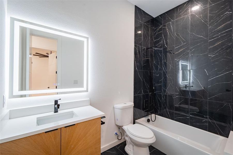 Full bathroom with tiled shower / bath, vanity, and toilet