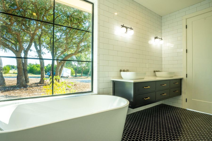 Bathroom with tile walls, double vanity, a soaking tub, and tile patterned floors