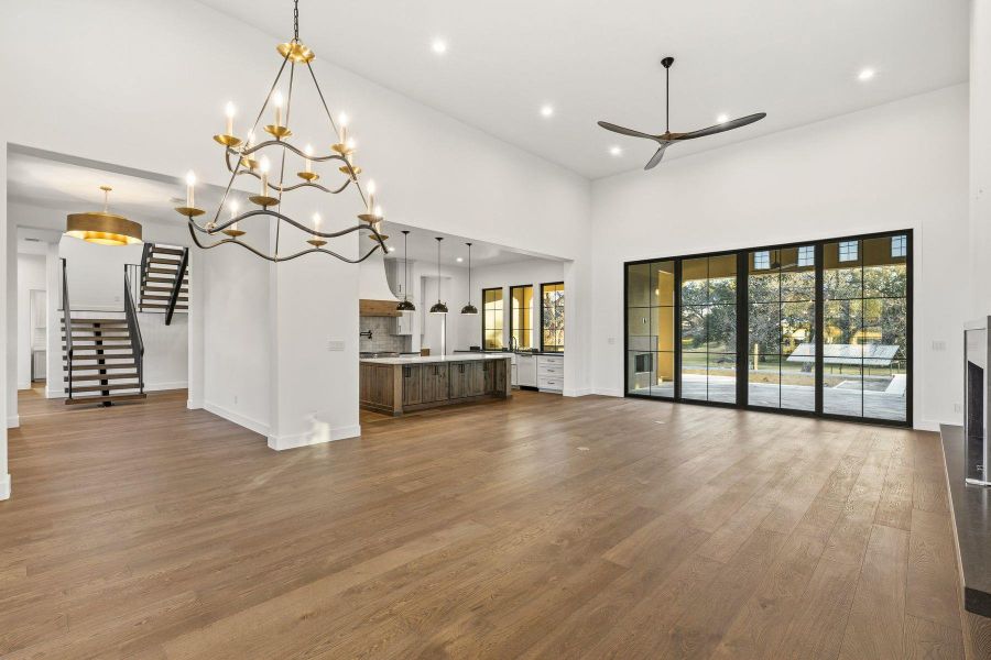 Unfurnished living room featuring dark wood-type flooring, a high ceiling, suspended lighting, and a ceiling fan