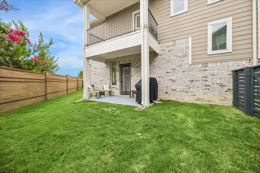 Enjoy a private, fully fenced backyard with a spacious side yard, lush green lawn, covered patio, and balcony perfect for relaxing or entertaining outdoors.