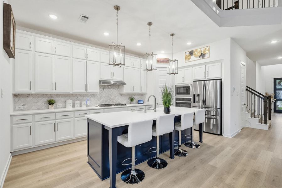 This exquisite kitchen boasts stainless steel appliances, a large kitchen island, and modern pendant lighting, creating a sophisticated and functional space perfect for entertaining and culinary excellence.