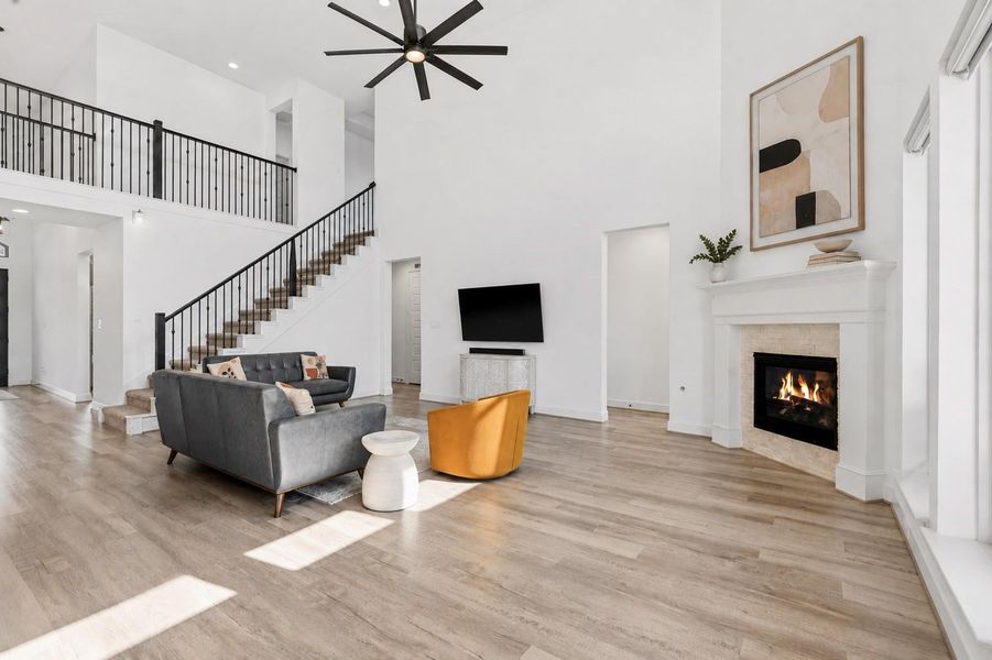 This open concept, two-story living room features soaring ceilings and an abundance of natural light. Connecting you to the primary bedroom suite, the second floor, or to the covered patio- this space creates an inviting atmosphere perfect for both everyday living and entertaining. A seamless blend of style, comfort, and sophistication throughout.