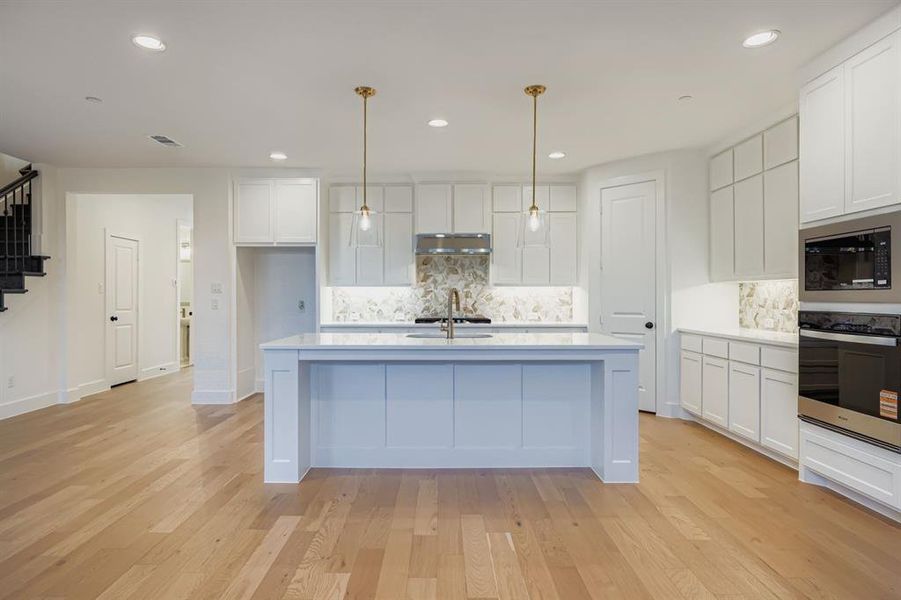 Kitchen with white cabinets, hanging light fixtures, decorative backsplash, and recessed lighting Kitchen with white cabinets, hanging light fixtures, decorative backsplash, and recessed lighting