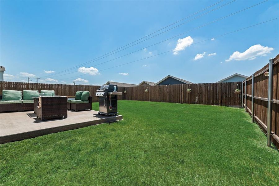Fenced backyard featuring an outdoor hangout area and a patio Fenced backyard featuring an outdoor hangout area and a patio