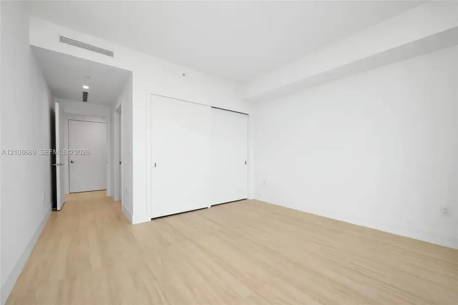 Interior space featuring wood-finish flooring, white walls, and built-in closet with sliding doors