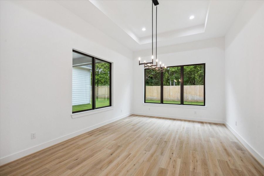 Walls of windows bring in natural light and views of the backyard, while a modern chandelier and tray ceiling add depth and sophistication to this versatile dining space. Walls of windows bring in natural light and views of the backyard, while a modern chandelier and tray ceiling add depth and sophistication to this versatile dining space.