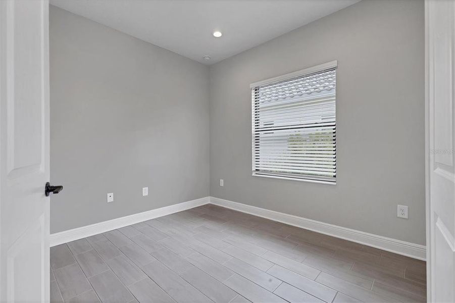 Den/office off of foyer with wood look ceramic tile.