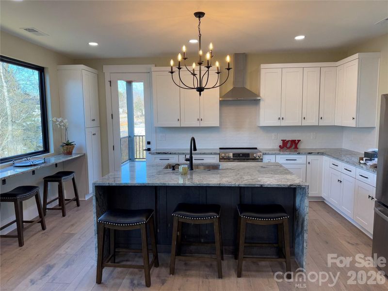 Large kitchen with island, seating area with sunset views and entry to covered veranda
