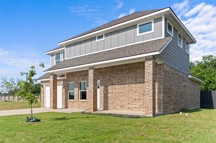 View of front of house featuring board and batten siding, brick siding, driveway, a front yard, and a shingled roof View of front of house featuring board and batten siding, brick siding, driveway, a front yard, and a shingled roof