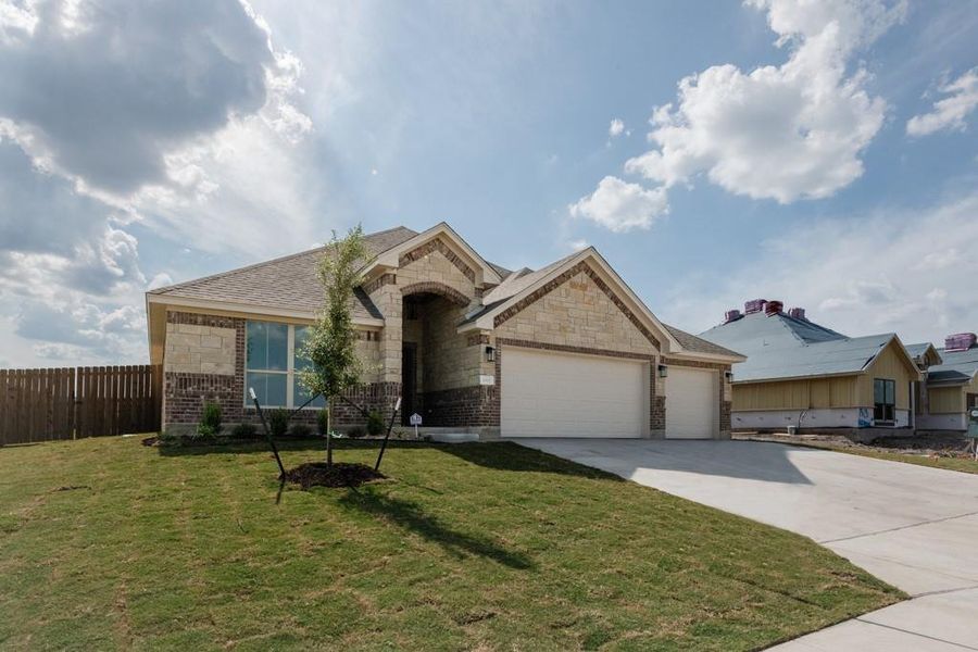View of front of property featuring brick siding, concrete driveway, an attached garage, and stone siding View of front of property featuring brick siding, concrete driveway, an attached garage, and stone siding