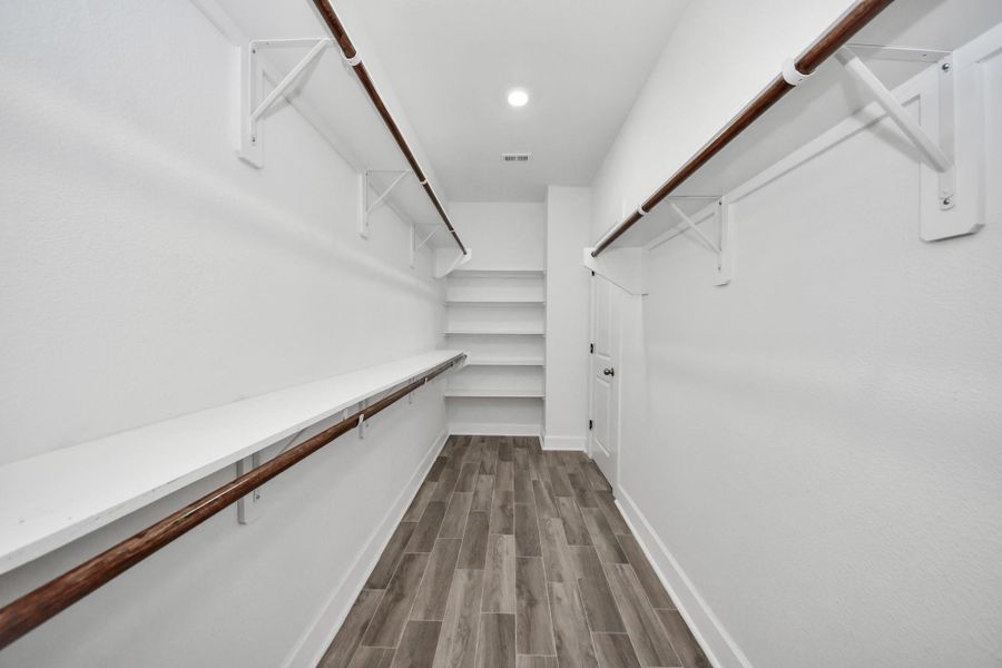 Spacious walk-in closet with ample hanging space, built-in shelves. Bright, with a modern, clean design.