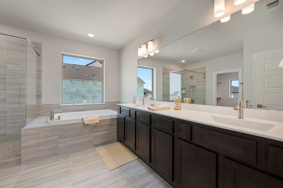 Full bath featuring double vanity, a garden tub, a stall shower, a fireplace, and light tile patterned floors