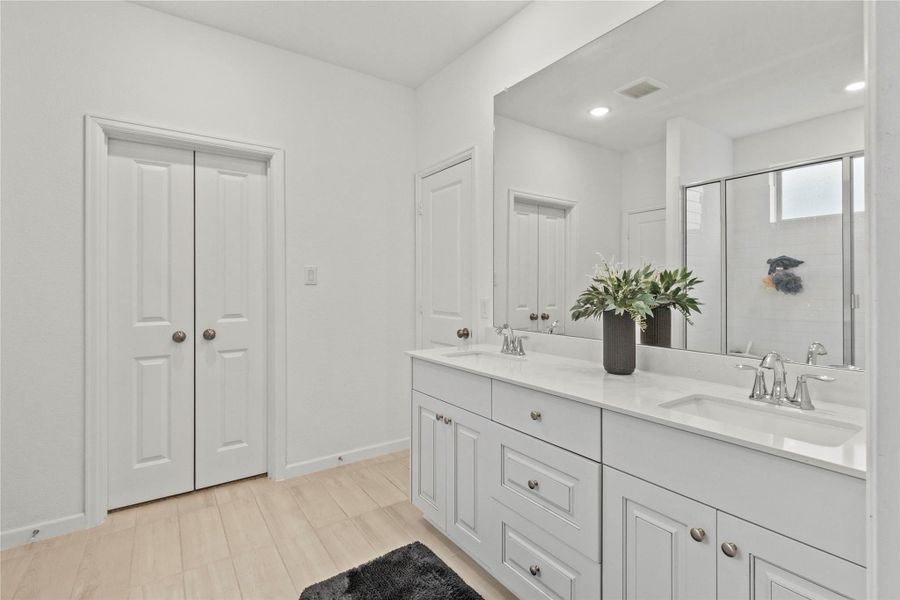 Bright and spacious bathroom featuring a double vanity with sleek countertops, ample storage, and a modern shower area for a luxurious feel. Bright and spacious bathroom featuring a double vanity with sleek countertops, ample storage, and a modern shower area for a luxurious feel.
