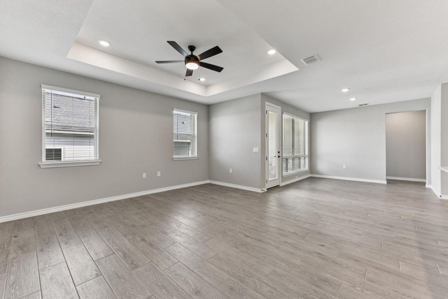 Unfurnished room featuring a tray ceiling, light wood-type flooring, recessed lighting, ceiling fan, and healthy amount of natural light Unfurnished room featuring a tray ceiling, light wood-type flooring, recessed lighting, ceiling fan, and healthy amount of natural light