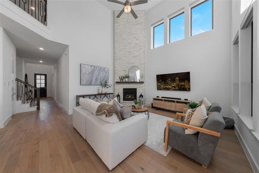 Living area featuring baseboards, a towering ceiling, wood finished floors, stairs, and a fireplace